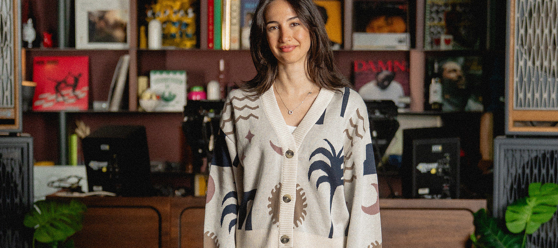 Woman wearing Summer Knitwear standing in a room with shelves and decor