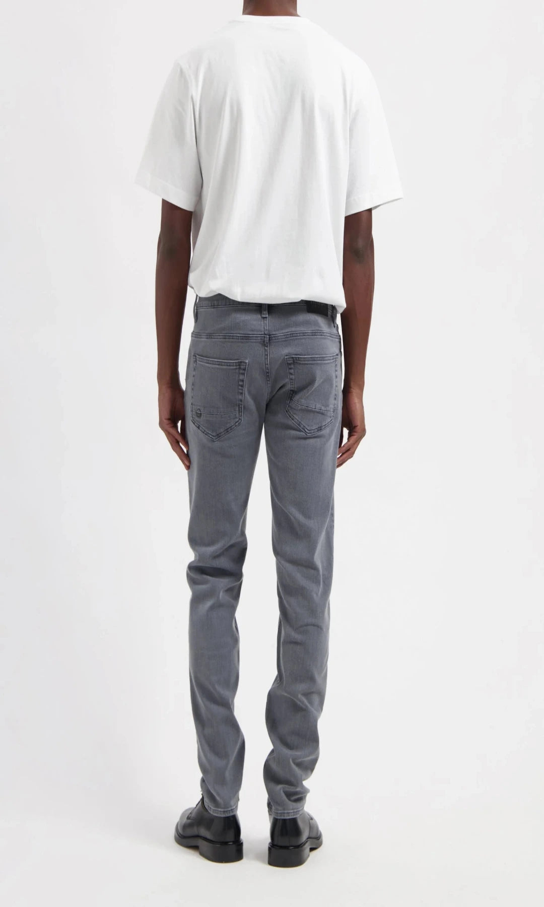 Person wearing gray jeans and a white t-shirt on a white background